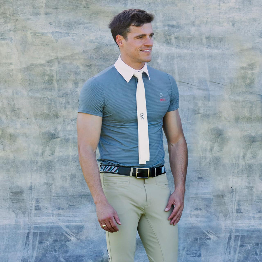 An equestrian model wearing the Balck Adamo shirt by Emcee Apparel in front of a grey background