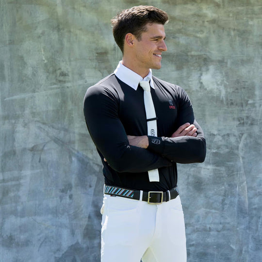 An equestrian model wearing the Balck Marco shirt by Emcee Apparel in front of a grey background