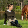 Equestrina model sitting in front of a lake and a horse wearing the Valentino shirt by Emcee Apparel in black